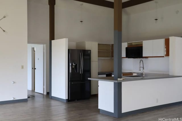 kitchen featuring a sink, dark wood-type flooring, white cabinets, a towering ceiling, and black refrigerator with ice dispenser