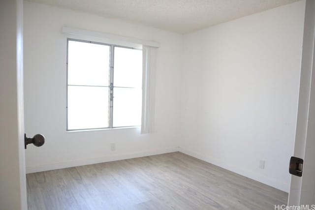 empty room featuring a textured ceiling, baseboards, and wood finished floors