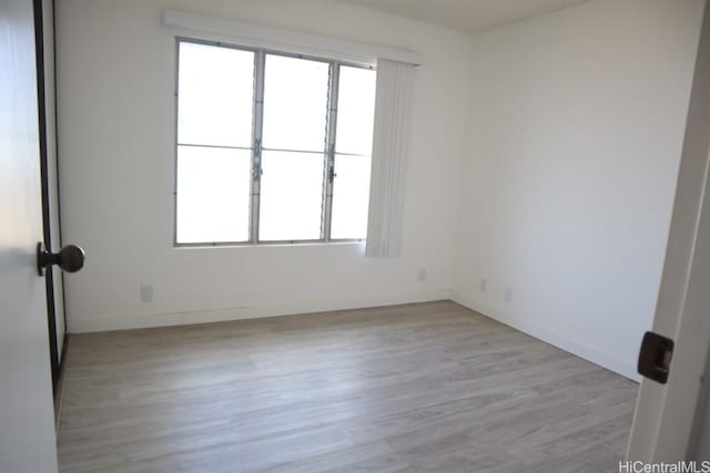 spare room with a healthy amount of sunlight, light wood-style floors, and baseboards