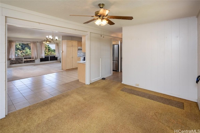 empty room with light tile patterned floors, light colored carpet, and ceiling fan with notable chandelier