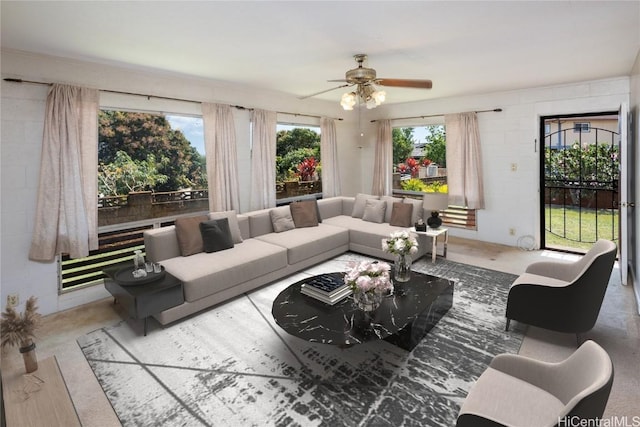 living room featuring concrete block wall and ceiling fan