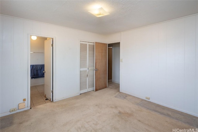 unfurnished bedroom featuring ensuite bath, carpet, a closet, and a textured ceiling