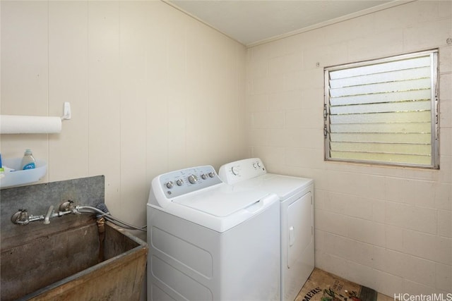 clothes washing area with laundry area, washer and dryer, concrete block wall, and a sink