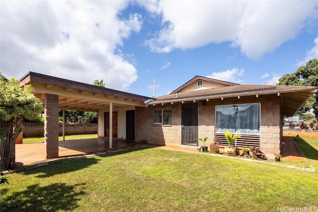 view of front of house with concrete block siding, a front lawn, a carport, and a patio