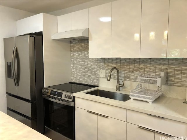 kitchen featuring a sink, decorative backsplash, light countertops, stainless steel appliances, and under cabinet range hood