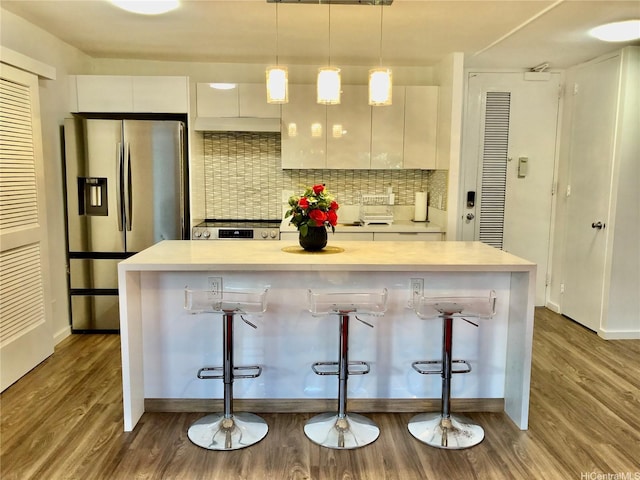 1519 Nuuanu Ave Unit 142, Honolulu, HI 96817 - kitchen featuring white cabinets, dark wood finished floors, decorative backsplash, appliances with stainless steel finishes, and a breakfast bar area