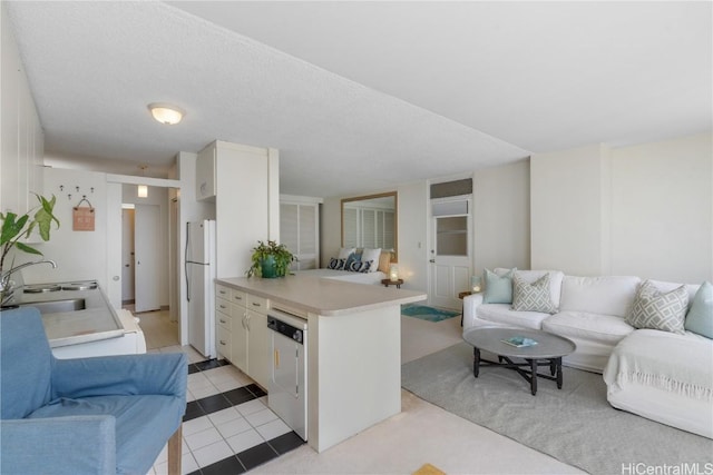 kitchen featuring open floor plan, dishwashing machine, a peninsula, freestanding refrigerator, and a sink