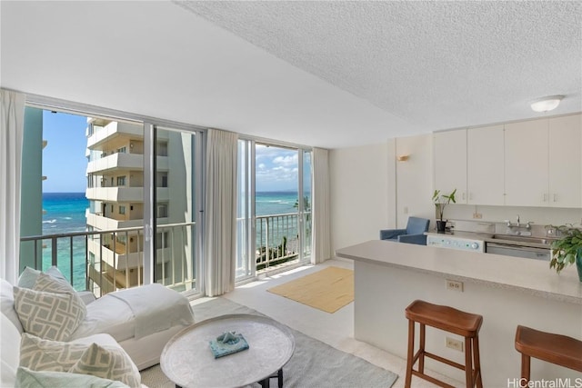 living area with a textured ceiling, a water view, and expansive windows