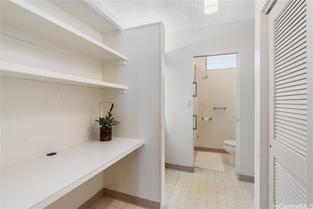 interior space with toilet, baseboards, a closet, and a textured ceiling