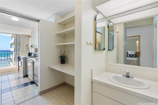 bathroom with tile patterned floors, a water view, washer / dryer, and vanity