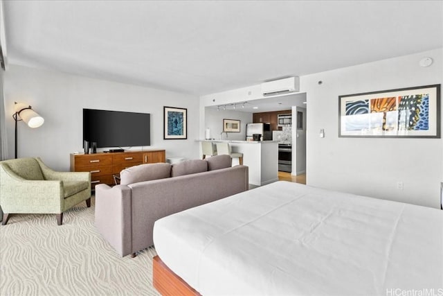 bedroom with a wall unit AC, light wood-style floors, and freestanding refrigerator