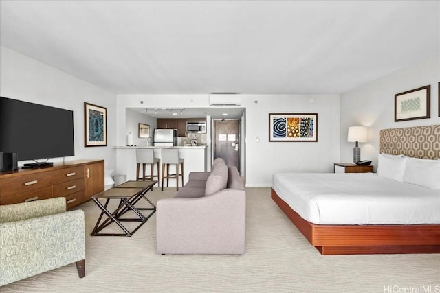 bedroom with an AC wall unit, track lighting, freestanding refrigerator, baseboards, and light colored carpet