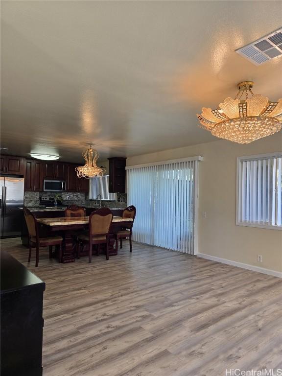 dining room with a notable chandelier, baseboards, visible vents, and light wood-type flooring