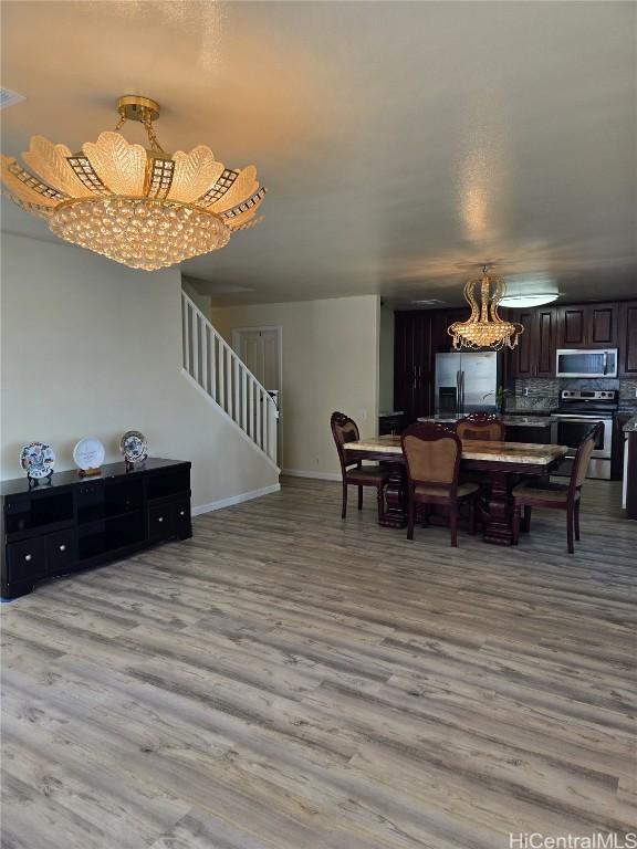 dining area featuring stairway, baseboards, a notable chandelier, and light wood-style flooring