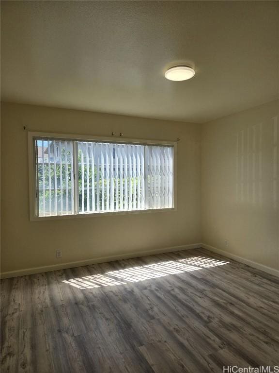 empty room with a healthy amount of sunlight, baseboards, and wood finished floors