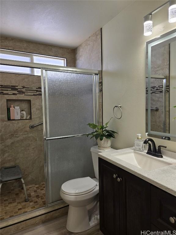 full bath with vanity, a shower stall, toilet, and wood finished floors