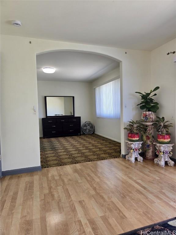 interior space featuring arched walkways, baseboards, and wood finished floors