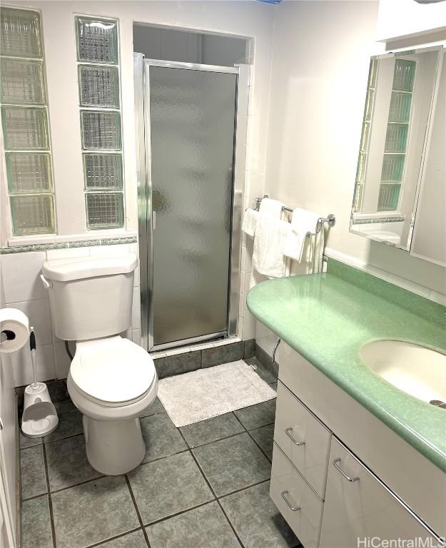 bathroom featuring tile patterned floors, vanity, a shower stall, and toilet