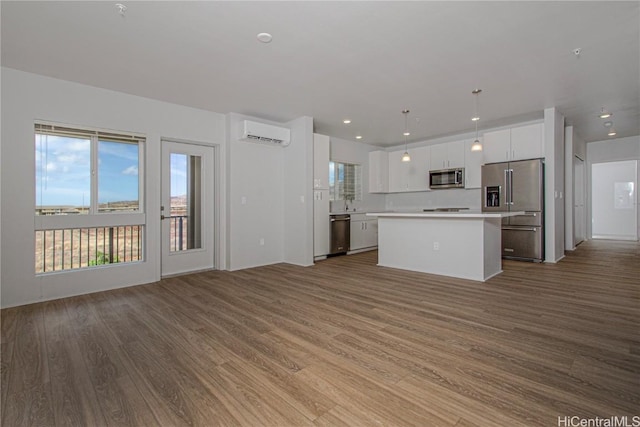 kitchen with a wall mounted AC, wood finished floors, a kitchen island, and stainless steel appliances