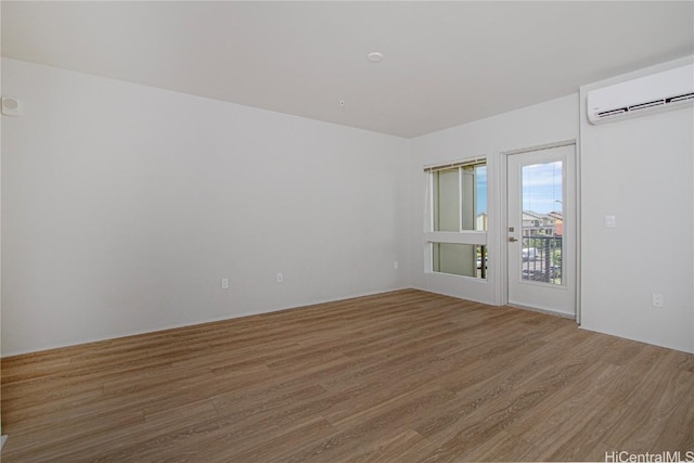 spare room with wood finished floors and a wall unit AC