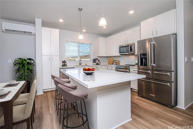 kitchen with an AC wall unit, a sink, a kitchen island, stainless steel appliances, and a breakfast bar area