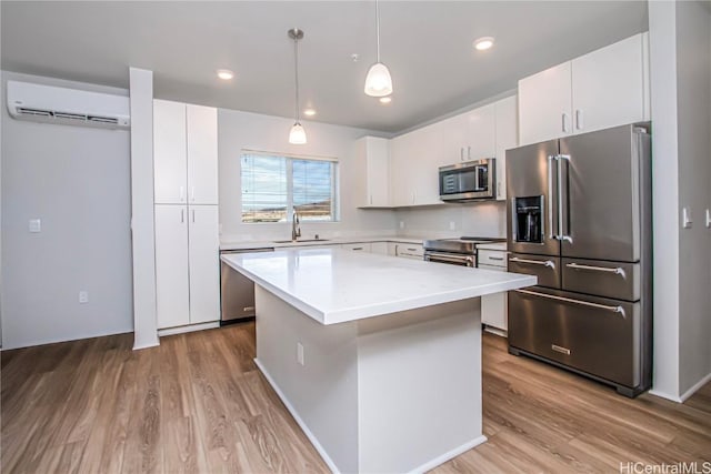 kitchen with a wall mounted air conditioner, light wood-style floors, appliances with stainless steel finishes, and a sink