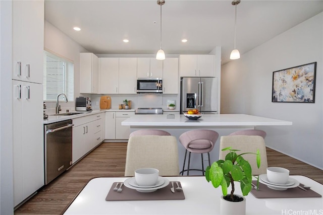 kitchen featuring a sink, stainless steel appliances, light countertops, a kitchen breakfast bar, and a center island