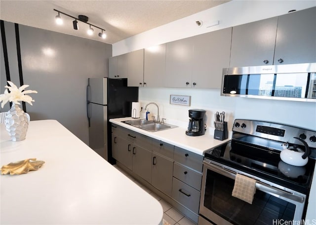 kitchen with gray cabinets, a sink, light countertops, appliances with stainless steel finishes, and a textured ceiling