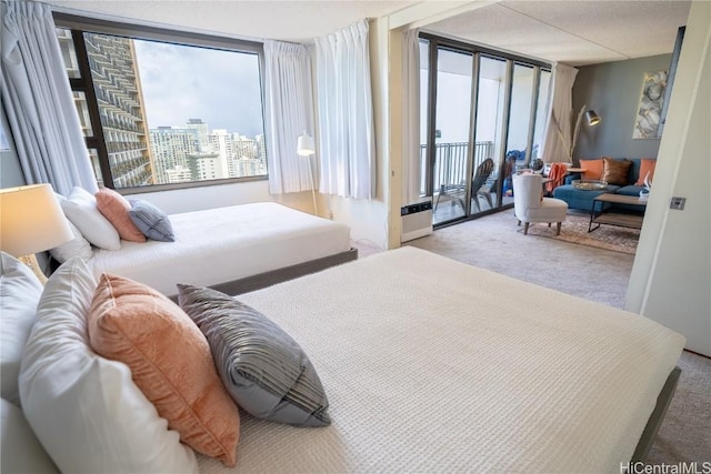 bedroom featuring a wall of windows, a view of city, access to outside, and carpet floors