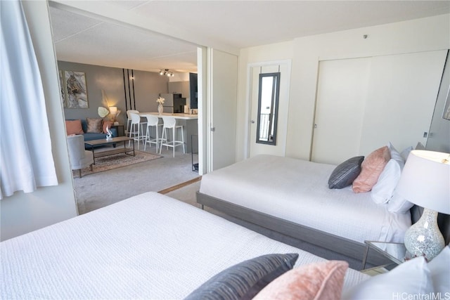 carpeted bedroom featuring a closet and freestanding refrigerator