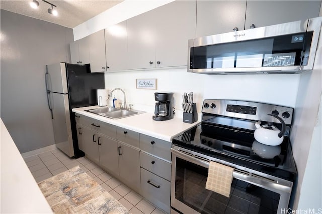 kitchen with light tile patterned floors, gray cabinetry, appliances with stainless steel finishes, and a sink