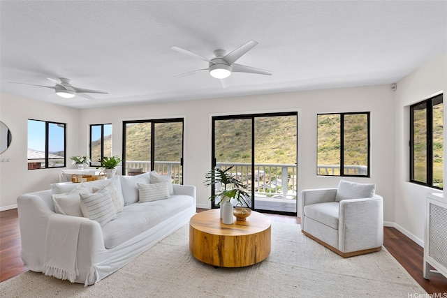 living room with baseboards, a ceiling fan, and wood finished floors
