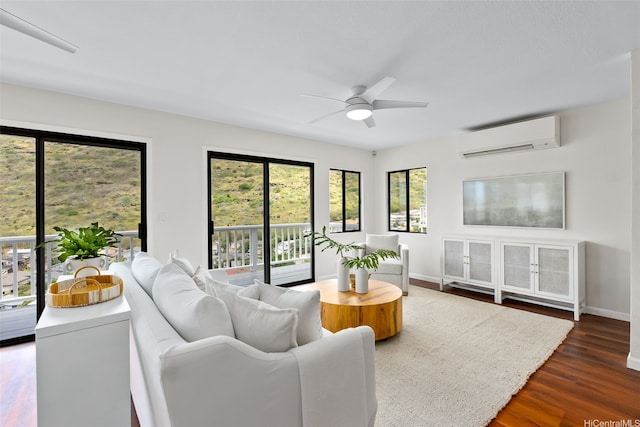 living room featuring baseboards, a ceiling fan, an AC wall unit, and dark wood-type flooring