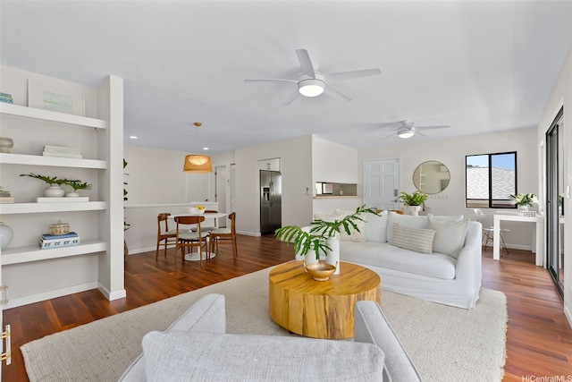 living area with a ceiling fan, baseboards, built in shelves, and wood finished floors