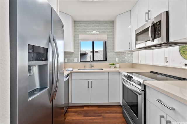 kitchen with a sink, light countertops, stainless steel appliances, and white cabinetry