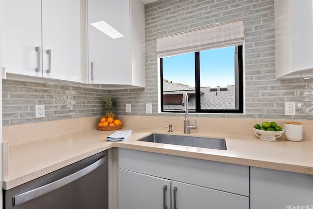 kitchen with white cabinets, tasteful backsplash, a sink, and dishwasher