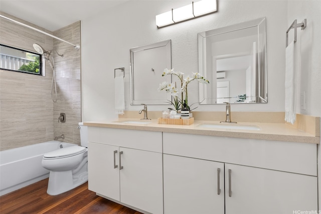 bathroom with a sink, double vanity, toilet, and wood finished floors