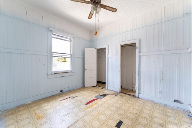 unfurnished bedroom featuring tile patterned floors, baseboards, multiple closets, and a ceiling fan