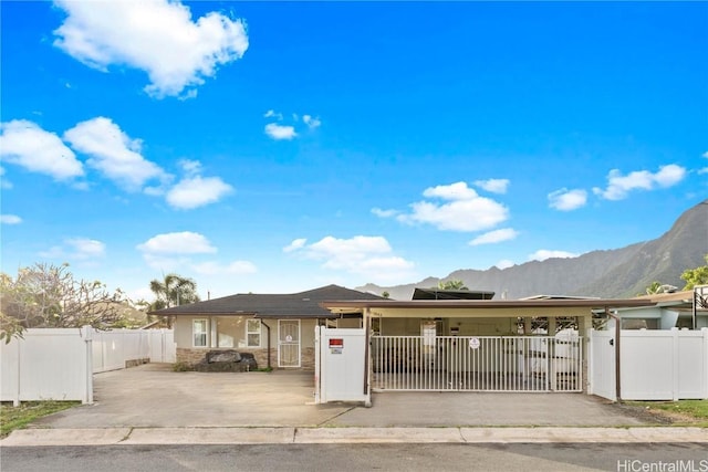 single story home with a fenced front yard, stone siding, a mountain view, and a gate