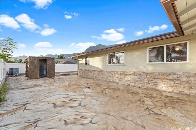 view of side of property with a patio, a fenced backyard, a mountain view, and stucco siding