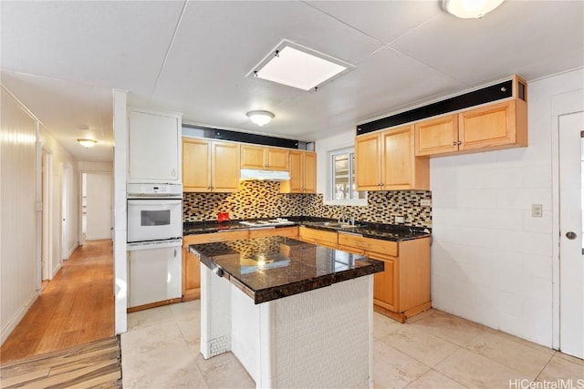 kitchen with light brown cabinetry, backsplash, white appliances, and dark countertops