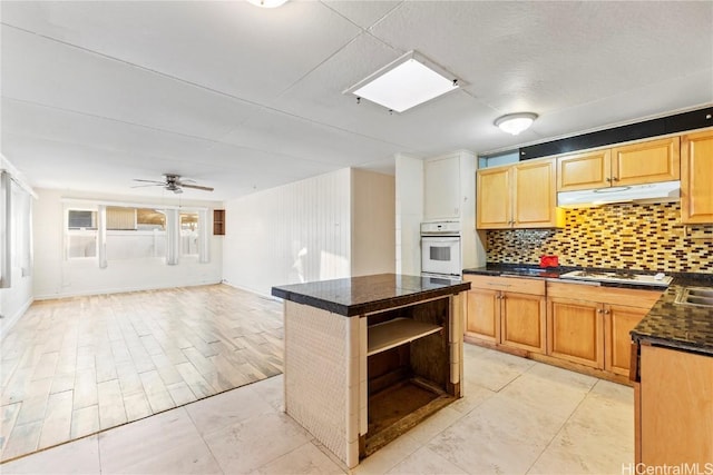 kitchen with under cabinet range hood, open shelves, a kitchen island, open floor plan, and decorative backsplash