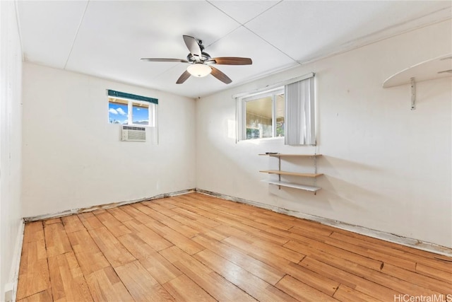 spare room featuring light wood-style flooring, cooling unit, and a ceiling fan