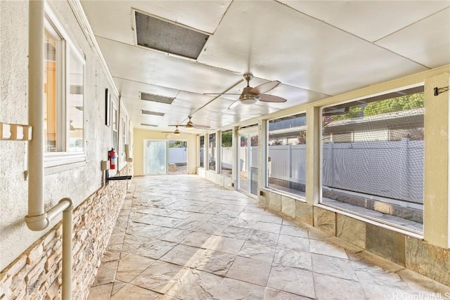 unfurnished sunroom featuring ceiling fan