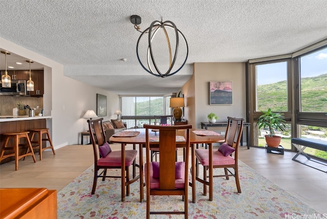 dining area featuring a wall of windows, light wood-type flooring, a wealth of natural light, and a textured ceiling