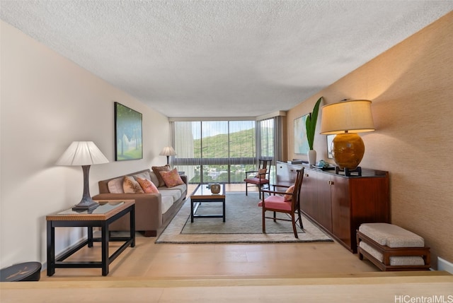 living area with floor to ceiling windows, wood finished floors, and a textured ceiling