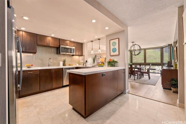 kitchen featuring tasteful backsplash, floor to ceiling windows, light countertops, a peninsula, and stainless steel appliances
