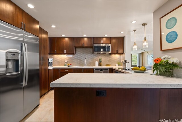 kitchen featuring a peninsula, a sink, decorative backsplash, light countertops, and stainless steel appliances