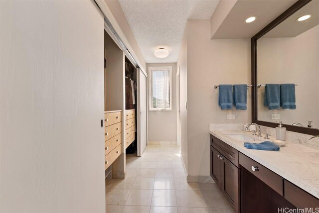 bathroom with vanity, baseboards, recessed lighting, tile patterned flooring, and a textured ceiling