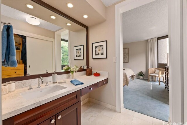bathroom featuring tile patterned floors, a textured ceiling, recessed lighting, baseboards, and vanity